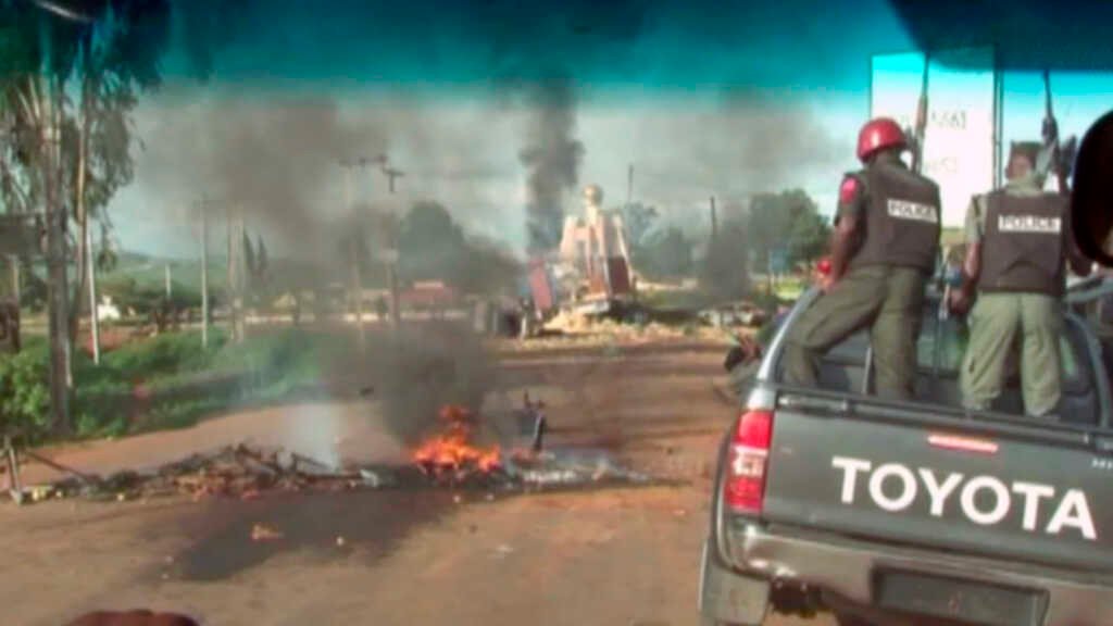 Cristãos nigerianos deslocados fogem de suas casas em meio a conflito e vilarejo em chamas.
