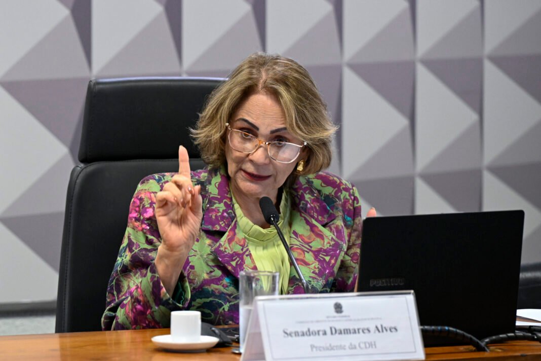 Senadora Damares Alves segura documentos em corredor do Congresso Nacional.