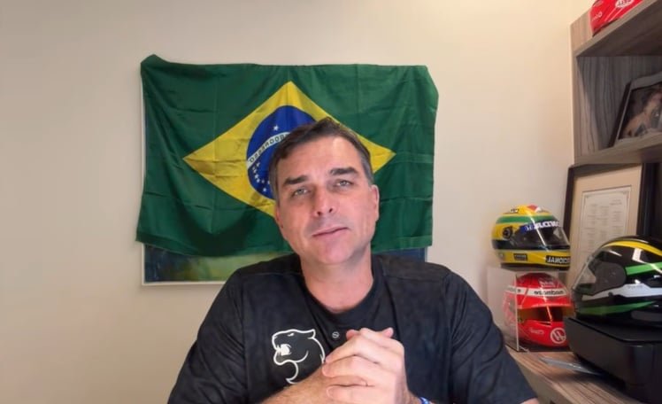 Flávio Bolsonaro em evento público, sorrindo e gesticulando.