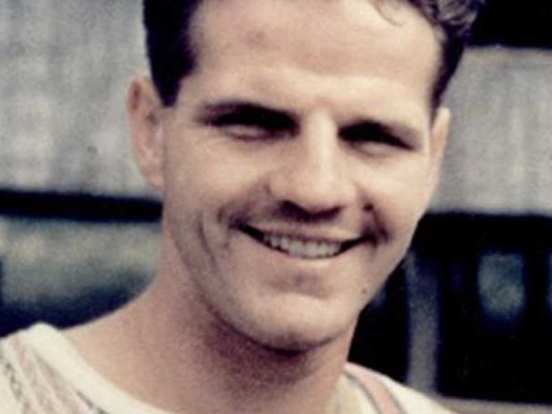 Missionário Jim Elliot em pé em uma floresta equatoriana, olhando com determinação.