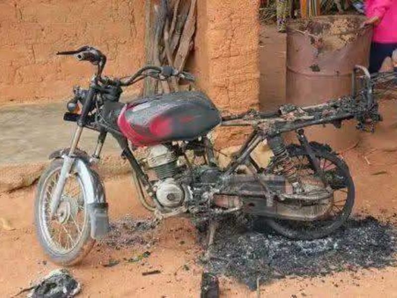 Aldeia nigeriana em ruínas após ataque de extremistas, com moradores expressando luto.