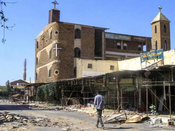 Interior de igreja destruída no Sudão com pastor em oração.