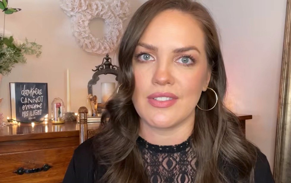 Kristina Costanza, ex-caçadora de fantasmas, olhando para a frente com expressão reflexiva após sua jornada espiritual.