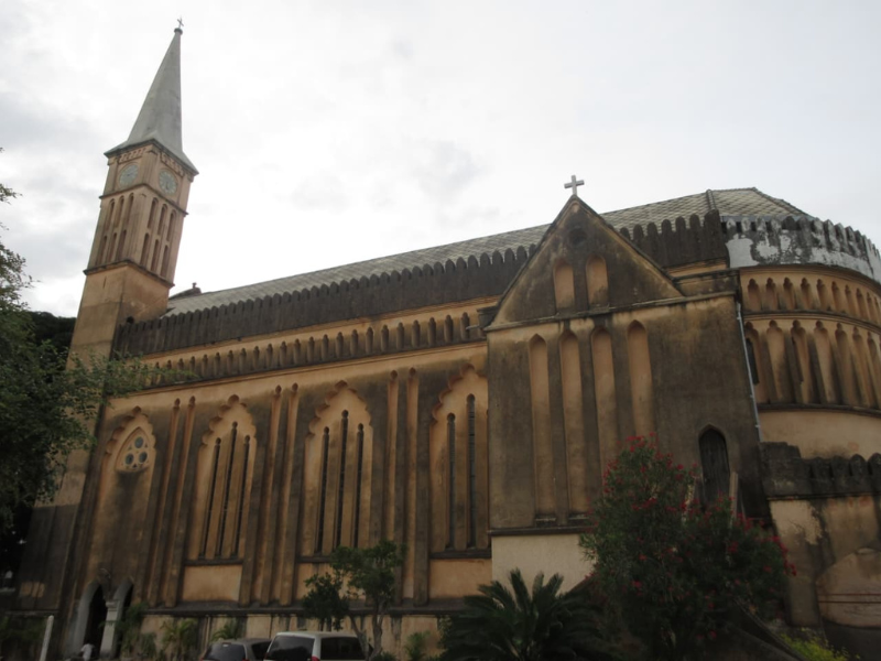 Cristãos tanzanianos saem de igreja em vila costeira, demonstrando cautela e fé.