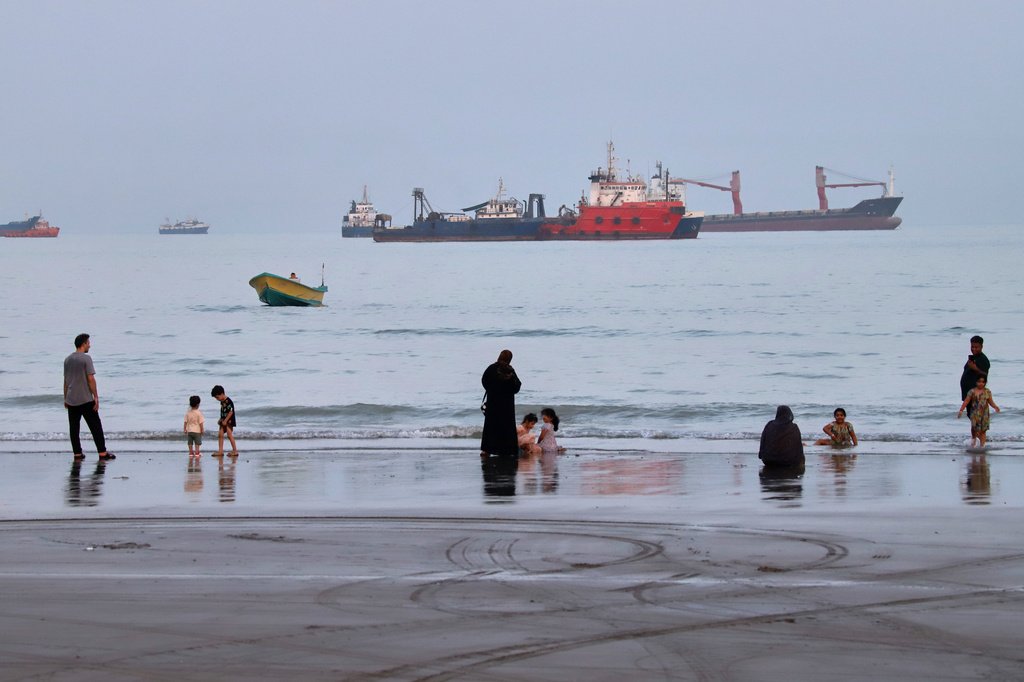 Navios petroleiros transitando pelo Estreito de Hormuz sob iluminação dramática, simbolizando o tráfego marítimo crucial.