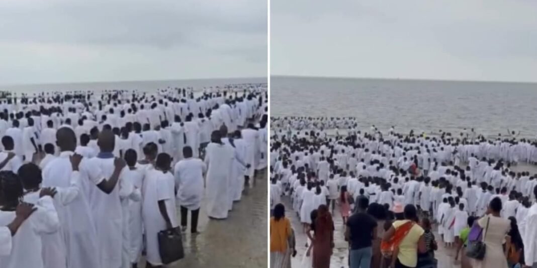 Multidão de pessoas vestidas de branco durante batismo em praia de Moçambique