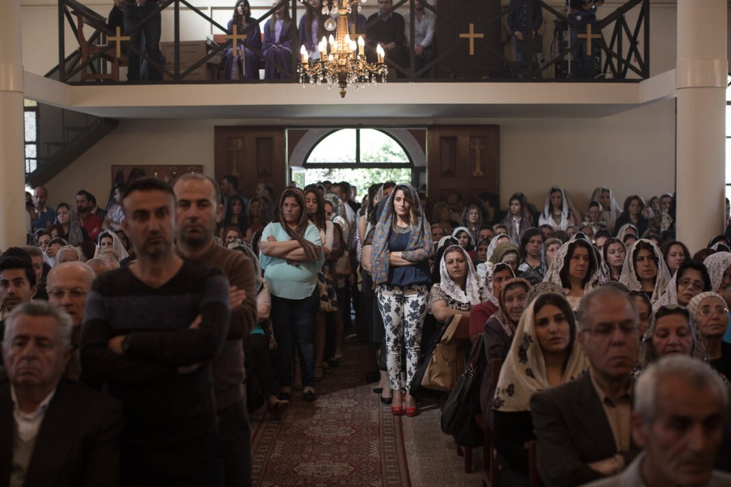 Fiéis cristãos reunidos em oração dentro de uma igreja histórica na Síria.