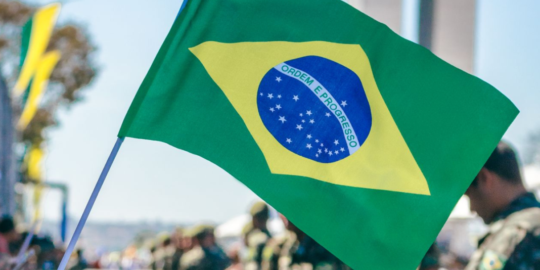 Manifestação popular com bandeira do Brasil ao fundo